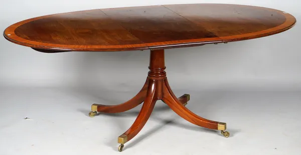 A George III style satinwood banded mahogany oval extending dining table on turned column and four downswept supports, one extra leaf, 107cm wide x 14