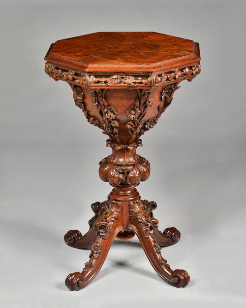 A Victorian figured walnut trumpet shaped work table, the octagonal lift top revealing a fitted birds eye maple interior over relief foliate carved bo