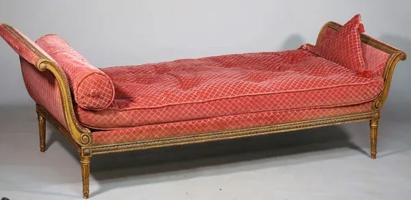 A Louis XVI style gilt framed double scroll end day bed with carved frieze on tapering fluted supports, 210cm wide x 74cm high.