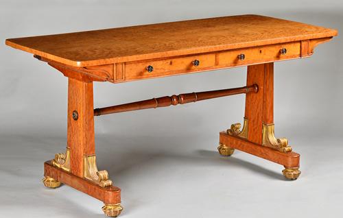 A William IV parcel gilt satin birch library table, the rounded rectangular top with a pair of frieze drawers and dummy opposing, on slab trestle end