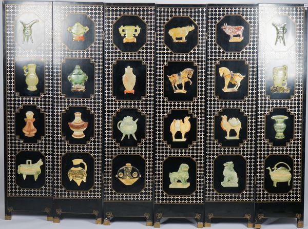 A mid-20th century Eastern black lacquer six fold screen, relief decorated with soapstone vessels, animals and mother-of-pearl trellis with gilt highl