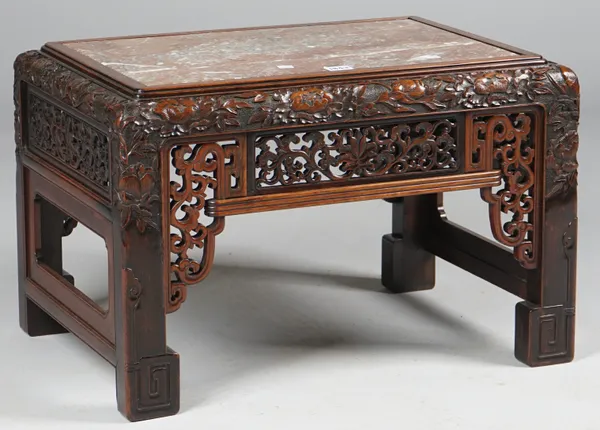 A late 19th century Chinese rectangular low table, the marble inset top on a pierced and relief floral carved base, on four block supports, 60cm wide