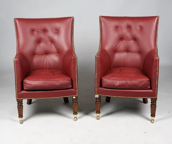 A pair of Regency style bungundy leather upholstered tub back armchairs on reeded mahogany supports, 60cm wide x 94cm high.