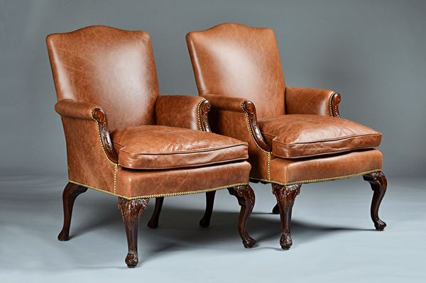 A pair of George III style studded brown leather upholstered armchairs with serpentine seats on carved mahogany supports, circa 1900, 66cm wide x 96cm