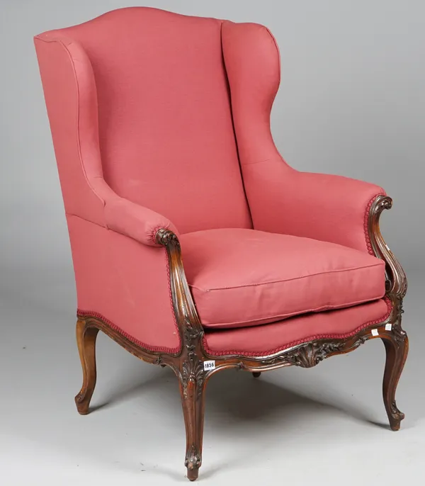 A Louis XV style wingback armchair on shell carved mahogany scroll supports, 72cm wide x 106cm high.