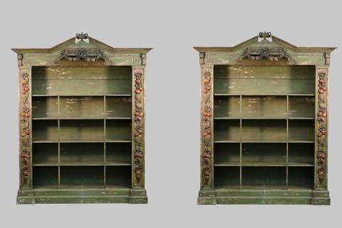A pair of Baroque revival green painted floor standing open bookcases, the urn mounted broken architectural cornice with polychrome fruiting swags on