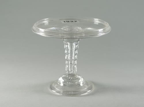 A glass patch stand, 18th century, the galleried round tray top supported on a bobbin stem and domed foot, 13cm diameter.