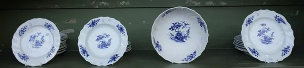 A Tournai porcelain blue and white part table service, late 18th century, painted with flowering plants and scattered flowers inside a scroll moulded