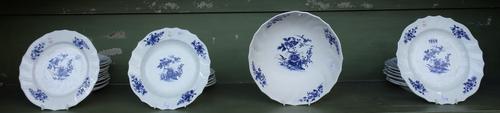 A Tournai porcelain blue and white part table service, late 18th century, painted with flowering plants and scattered flowers inside a scroll moulded