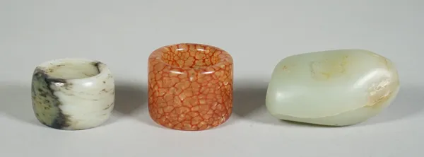 A Chinese jade pebble snuff bottle, probably 19th century, the stone with russet inclusions, 5cm high; also two Chinese archer's rings of various tone