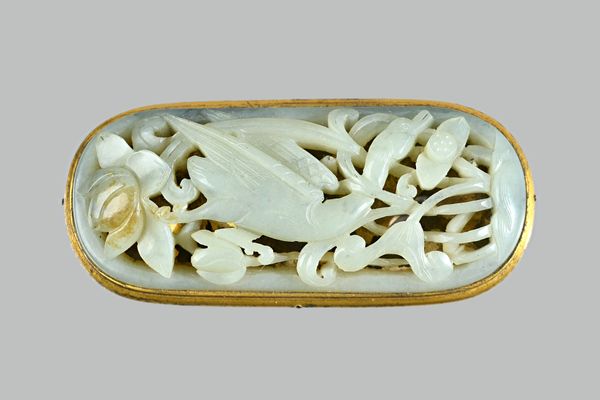 A Chinese celadon jade plaque, probably 17th/18th century, set with a gilt-metal mount, carved and pierced with a bird amongst lotus, the stone with b