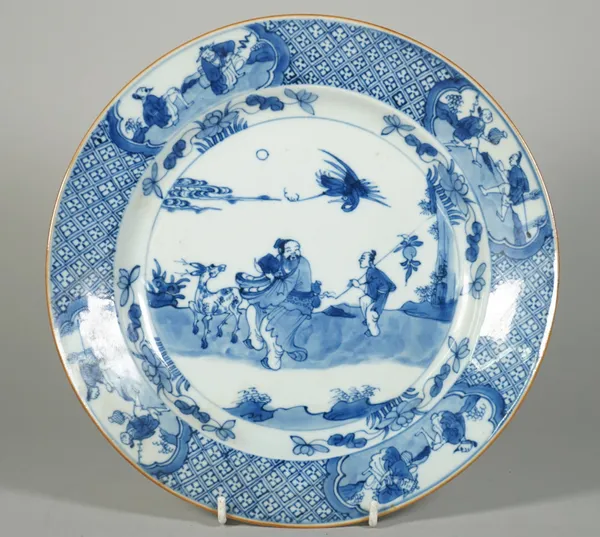 A Chinese blue and white porcelain plate, 18th century, painted in the centre with a figure in a landcsape with attendant and deer, inside a diaper pa