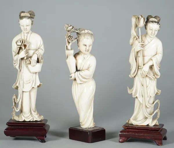 A pair of Chinese ivory figures of young women, early 20th century, each standing in long robes, one holding a basket with flowers, the other with lot