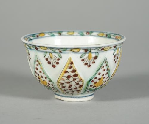 A Kutahya type teabowl, 18th century or later, the sides moulded with lappets painted with flowers alternating with a scale pattern, foliate border, (