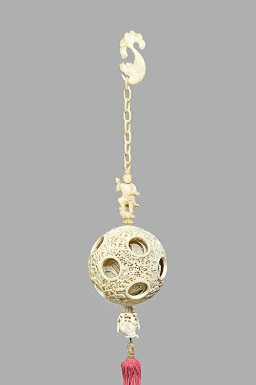 A Canton ivory puzzle ball, late 19th century, the outer ball pierced and carved with figures, pavilions and trees, containing around six inner geomet