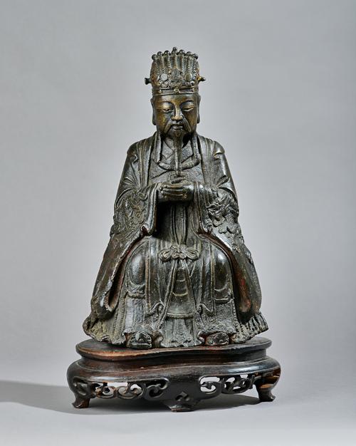 A Chinese bronze figure of a dignitary, Ming dynasty, seated in meditation with hands clasped, traces of gilding and red pigment, 34cm. high, later wo