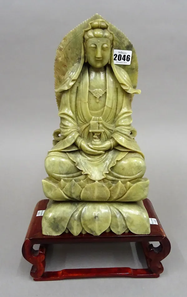 A large Chinese soapstone figure of Guanyin, late 19th/20th century, carved seated on a double lotus base, 33cm.high, wood stand, (2).