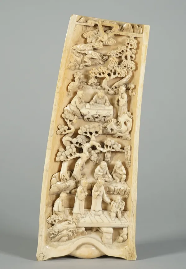 A Chinese ivory wrist rest, 19th century, deeply carved with scholars and attendants among pine and rockwork, the reverse carved with huts, trees and