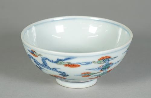 A small Chinese porcelain bowl. blue six character Yongzheng mark but later, painted in doucai style with two dragons amongst cloud scrolls, 9.5cm. di