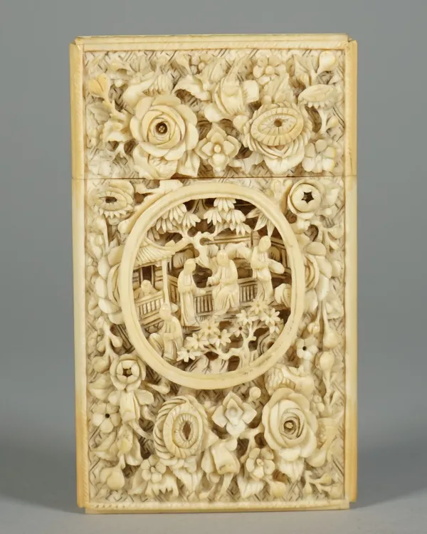 A Canton ivory rectangular card case, late 19th century, one side carved with an oval panel enclosing figures on a terrace against a ground filled wit