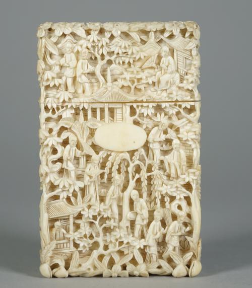 A Canton ivory rectangular card case, late 19th century, profusely carved with figures amongst trees and pavilions,one side with small oval cartouche,