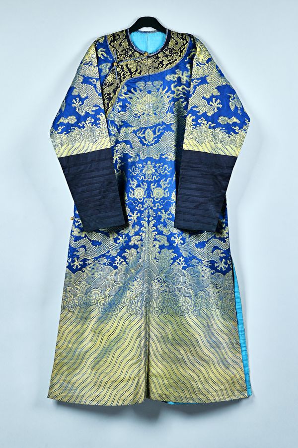 A Chinese blue-ground `eight dragon'  robe, circa 1900, decorated in gilt thread with eight dragons chasing flaming pearls amongst clouds, birds and a