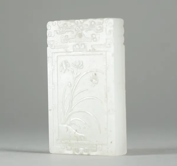 A Chinese white jade rectangular pendant, late 19th/20th century, one side carved in low relief with two insects and a flower, the reverse with three
