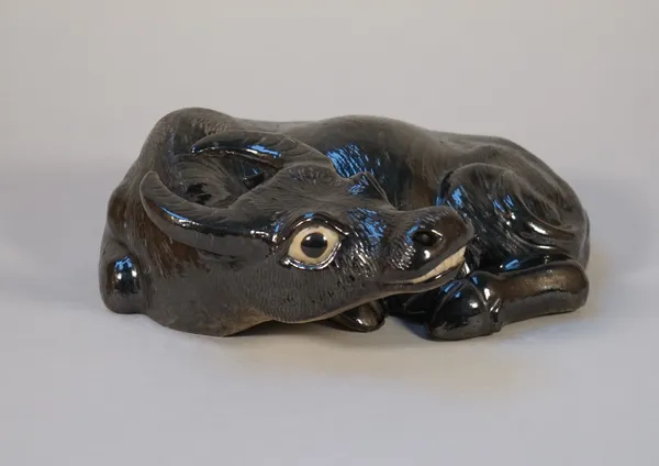 A Chinese porcelain figure of a recumbent water buffalo, probably 20th century, covered in a lustrous deep brown/black glaze, 26cm. wide.