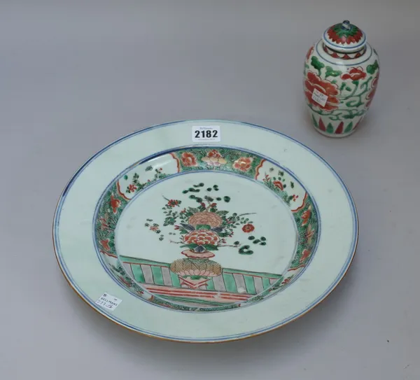 A Chinese famille-verte dish, Kangxi, painted in the centre with a vase of flowers inside a seeded green and floral border reserved with flower panels