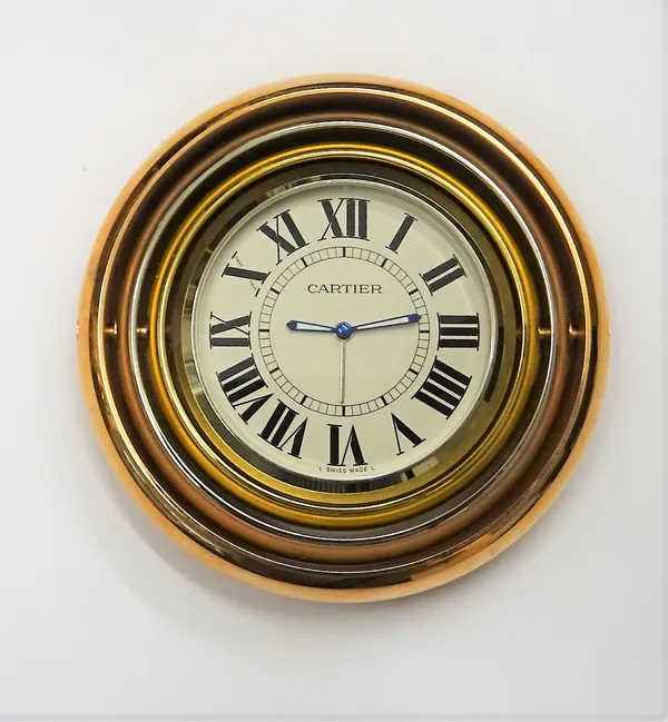 A Cartier three colour gold plated electronic travel alarm clock, the signed circular dial, with black Roman numerals, the case of triple ring concent