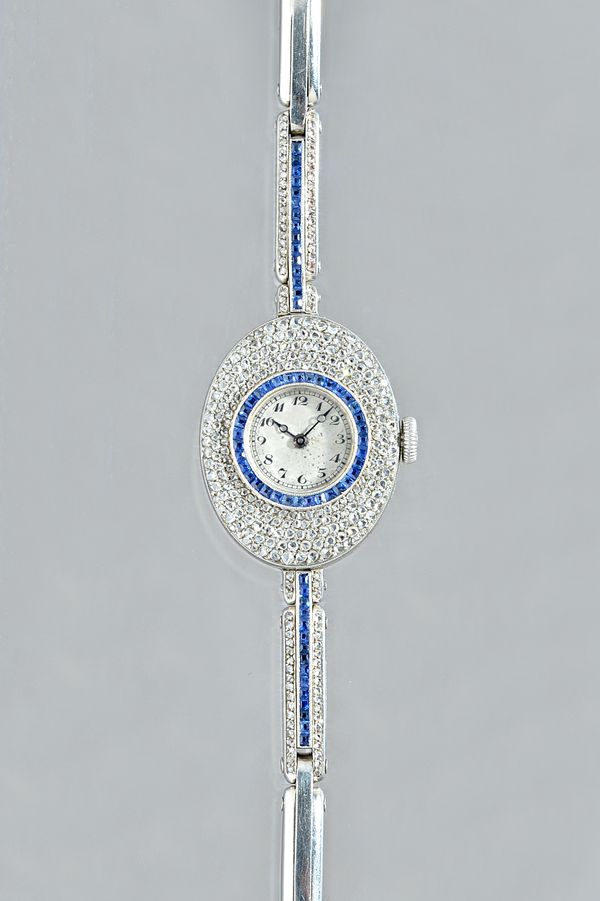 A lady's white gold, diamond and sapphire set, oval cased cocktail bracelet wristwatch, with an unsigned circular gilt jewelled lever movement, the ci