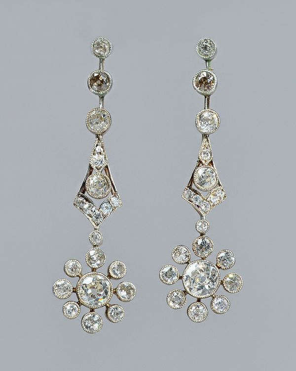 A pair of diamond set pendant cluster earrings, each cluster drop collet set with the principal cushion shaped diamond to the centre, in a surround of
