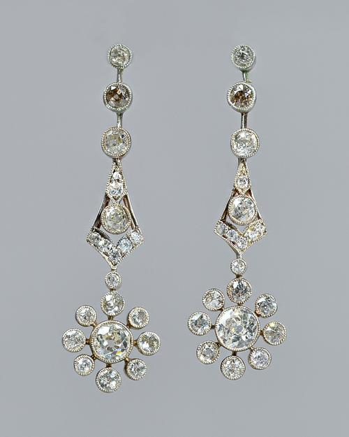 A pair of diamond set pendant cluster earrings, each cluster drop collet set with the principal cushion shaped diamond to the centre, in a surround of