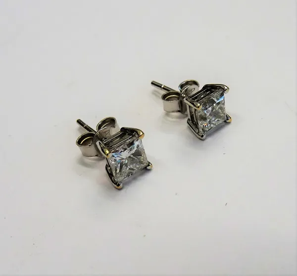 A pair of diamond single stone earstuds, each claw set with a princess cut diamond, the backs with unmarked post and butterfly clip fittings, detailed