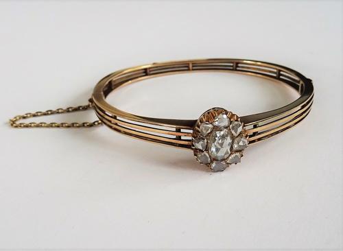 A diamond set hinged bangle, circa late 19th Century, set with a diamond cluster, the central oval rose cut diamond approximately 8.5mm x 5.8mm, in a