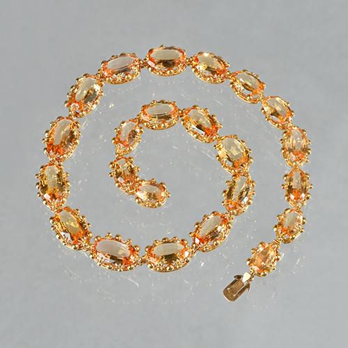 A 19th century gold and Imperial topaz necklace, formed as a row of twenty-three graduated oval cut Imperial topaz, the settings of stylized coronet f