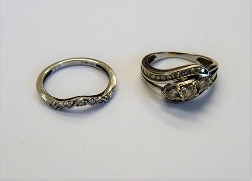 A white gold and diamond ring, claw set with the three principle circular cut diamonds at the centre, between two rows of small circular cut diamonds,