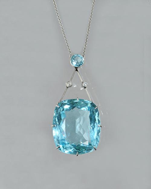 An aquamarine and diamond pendant necklace, claw set with the principal cushion shaped aquamarine to the drop and collet set with a smaller circular c
