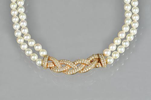 A two row cultured pearl choker necklace, suspended from a diamond set yellow gold clasp of platted design, pavé set throughout, with circular cut dia