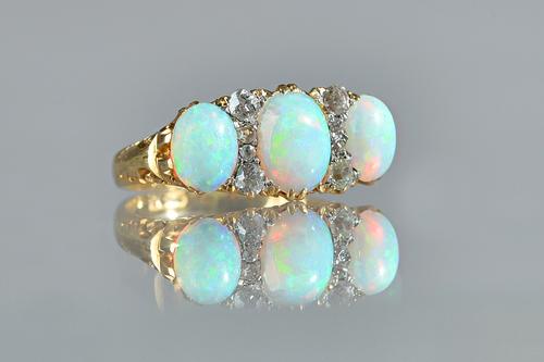 A gold, opal and diamond ring, mounted with three oval opals and with two rows of four small cushion shaped diamonds mounted at intervals, the mount d