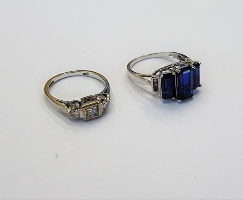 An 18ct white gold and diamond set three stone ring, mounted with a princess cut diamond to the centre between two claw set circular cut diamonds, rin