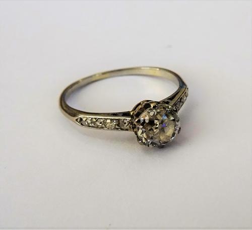 A diamond set solitaire ring, claw set with the principal cushion shaped diamond to the centre, between diamond set four stone shoulders, ring size O.