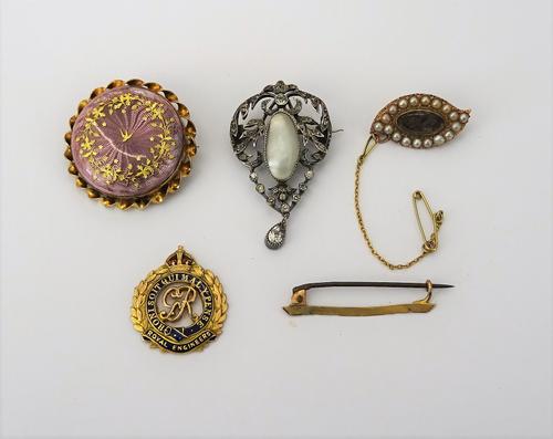 A gold brooch, glazed with an oval hair locket compartment to the centre, in a surround of half pearls, a gold and enamelled brooch designed as the ba