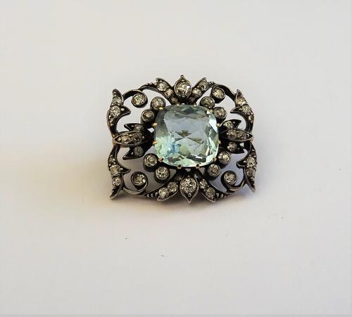 A gold backed and silver fronted aquamarine and diamond brooch, mounted with the cushion shaped aquamarine at the centre, within a shaped rectangular