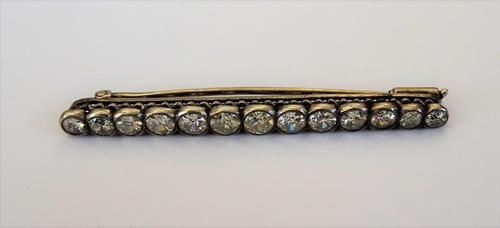 A diamond brooch, mounted with a row of thirteen cushion shaped diamonds, graduating in size to the centre stone, length 5.7cm.