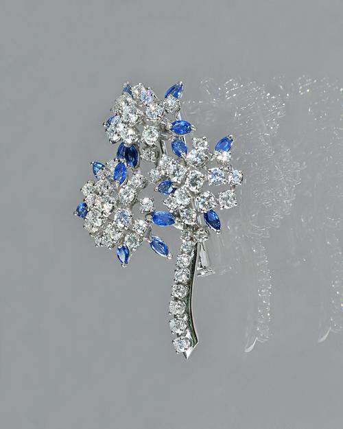 A white gold, sapphire and diamond brooch, designed as a triple flowerhead shaped spray, mounted with marquise shaped sapphires and with circular cut