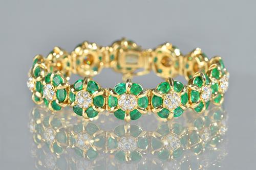 A gold, emerald and diamond bracelet, in a shaped circular cluster link design, each link mounted with seven circular cut diamonds to the link centre,