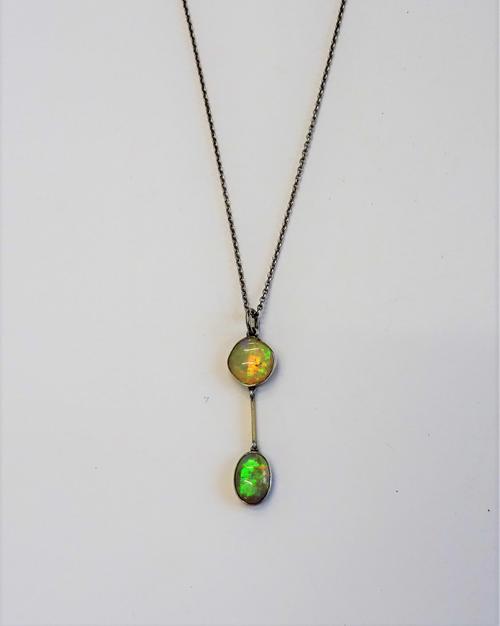 An opal two stone pendant, collet set with two opals, connected by a bar shaped division, on an oval link neckchain, with a boltring clasp.
