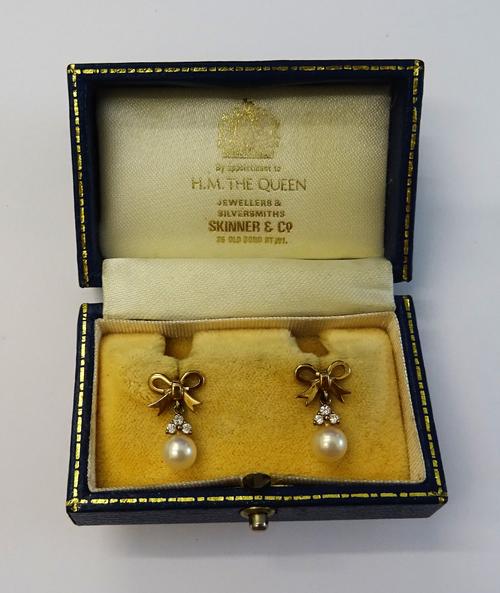 A pair of yellow precious metal, diamond and cultured pearl pendant earrings, of bow design, suspending a trefoil of circular cut diamonds and culture