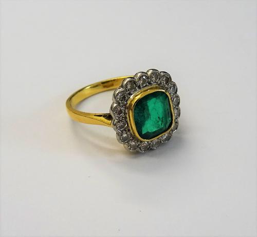 An 18ct gold, emerald and diamond dress ring, of cluster design, the central emerald collet set in a surround of circular cut diamonds, ring size K, g